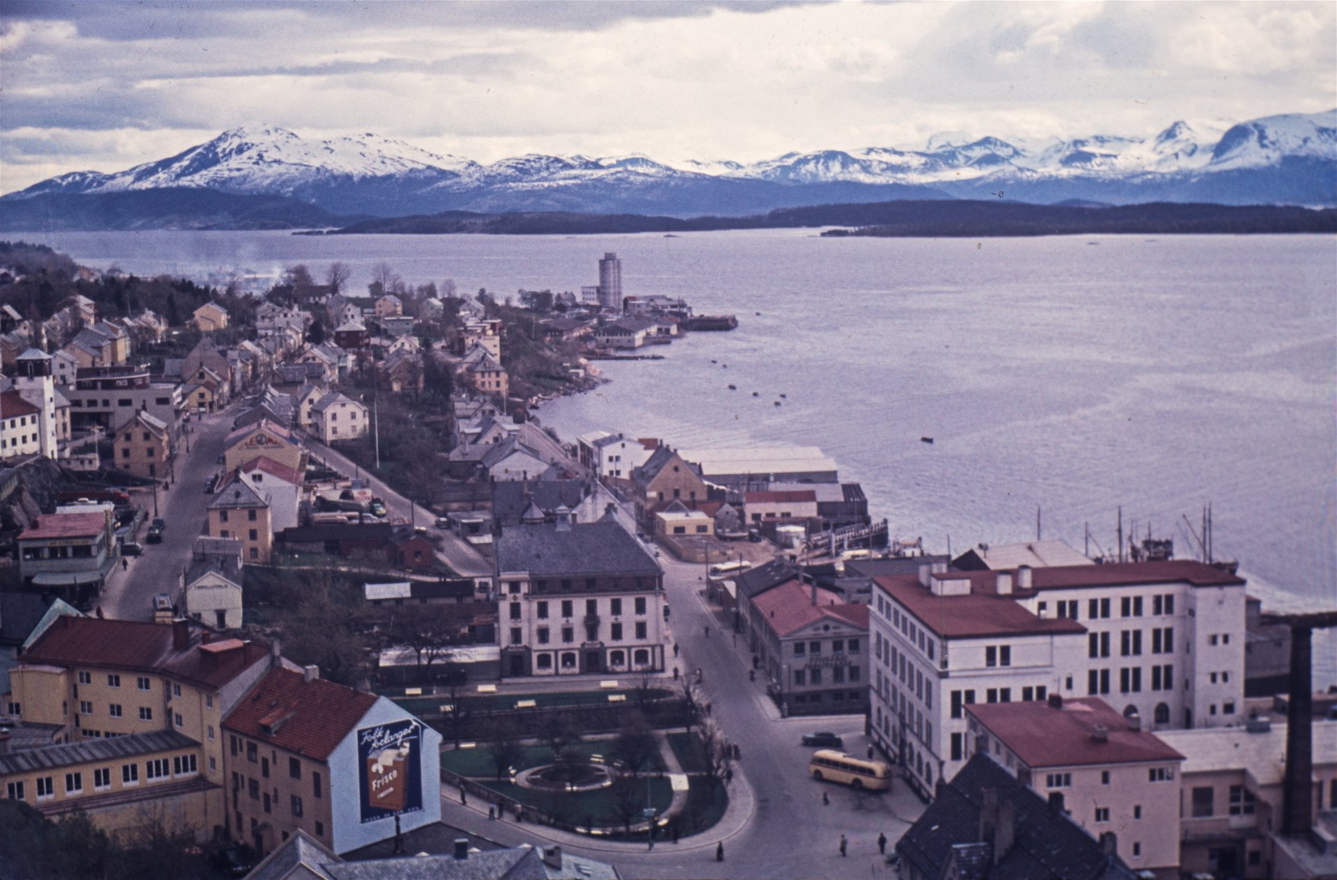 Byen sett østover fra kirketårnet. Fjorden og fjellrekka i bakgrunnen. Foto.